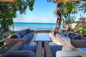 A patio with wicker furniture, a table, and a view of the ocean. - The Perfect Beachfront Escape - Sea Grove House (Weston)