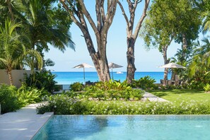 A pool area with a view of the ocean, surrounded by palm trees and lounge chairs. - The Perfect Beachfront Escape - Sea Grove House (Weston)