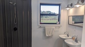 Ein Badezimmer mit Dusche, zwei Waschbecken, einem Fenster mit Aussicht und einem Handtuchhalter.