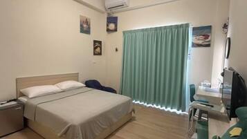 A hotel room with a bed, bedside table, and a desk with a chair.
