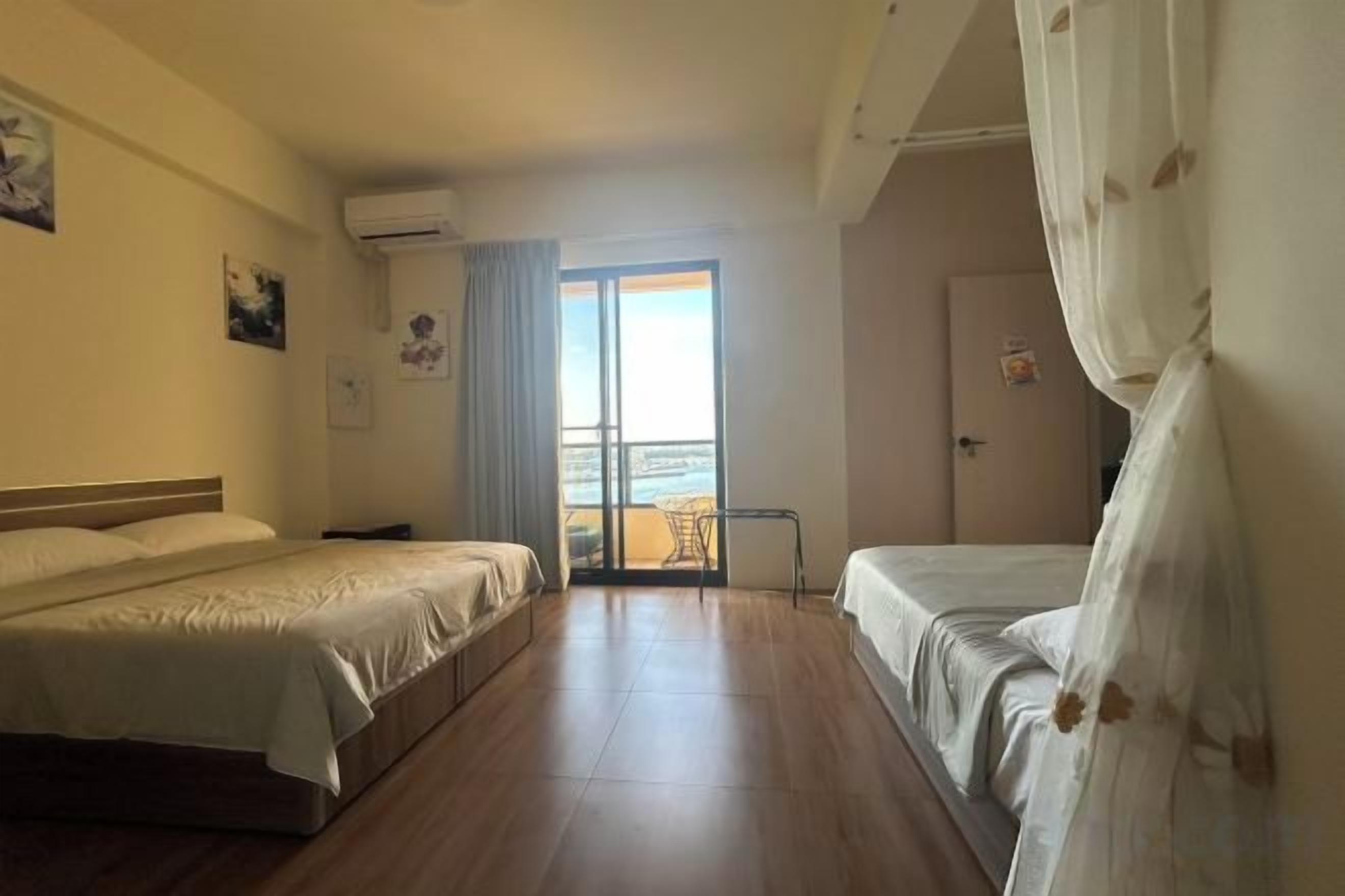 A hotel room with two beds, a balcony, and a view of the sea.