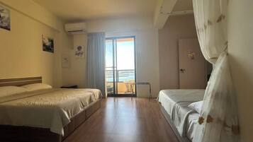A hotel room with two beds, a balcony, and a view of the sea.