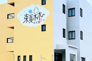 Un bâtiment à la façade jaune et à la partie blanche. On y voit un logo avec des caractères chinois et un motif représentant un nuage.