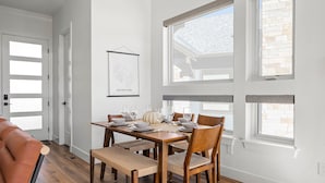 Un coin repas avec une table en bois dressée pour quatre personnes, entourée de chaises dont les assises sont en osier tressé.