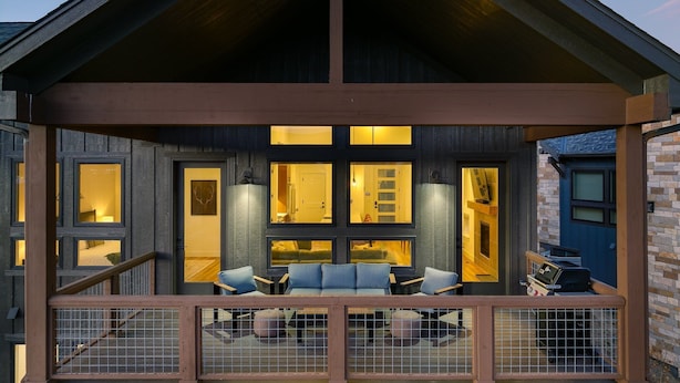 Une terrasse en bois à plusieurs niveaux, dotée d’un espace salon et d’un barbecue.