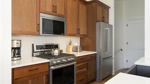 Une cuisine dotée de meubles en bois, d’appareils électroménagers en acier inoxydable, d’un four à micro-ondes, d’une cuisinière, d’un réfrigérateur et d’un grille-pain.