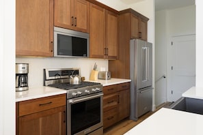 A kitchen with wooden cabinets, stainless steel appliances, a microwave, a stove, a refrigerator, and a toaster. - Downtown WP Chalet 50 I Hot Tub I Great Views I Car Charger I Bunks I Discounted Attractions (Winter Park)