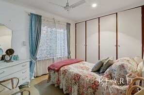 A bedroom with a bed, a dresser, a mirror, and a wardrobe.