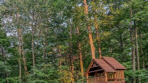 A wooden playground structure with a slide, surrounded by a wooded area. - Pine & Paddle | Family Cabin | Sleeps 7 (Hammond)