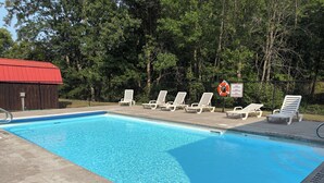 A swimming pool with lounge chairs and a lifebuoy sign. - Pine & Paddle | Family Cabin | Sleeps 7 (Hammond)