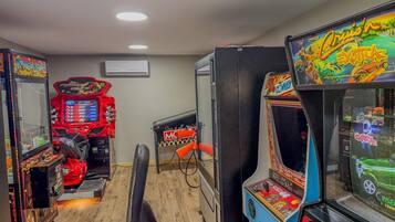 Une rangée de jeux d’arcade dans une pièce au plancher en bois et éclairée par un plafonnier.