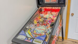 A pinball machine with a Monopoly theme, including a monitor displaying the game and various game elements inside. - Pine & Paddle | Family Cabin | Sleeps 7 (Hammond)
