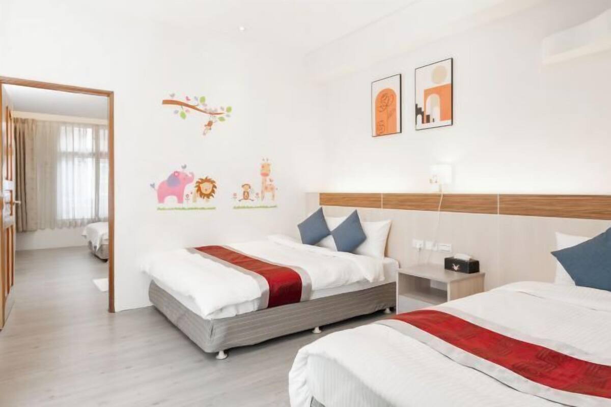 A hotel room with two beds, a wooden headboard, and a small bedside table with a lamp.