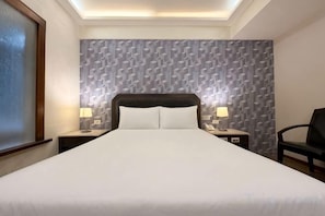 A hotel room with a large bed, two bedside tables with lamps, a chair, and a patterned wall. - I Hi Sanduo hotel (Kaohsiung)