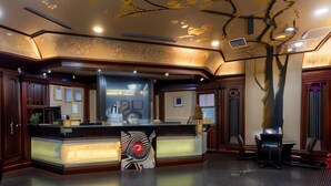 A reception area with a counter, a large tree sculpture, and a modern ceiling design. - I Hi Sanduo hotel (Kaohsiung)
