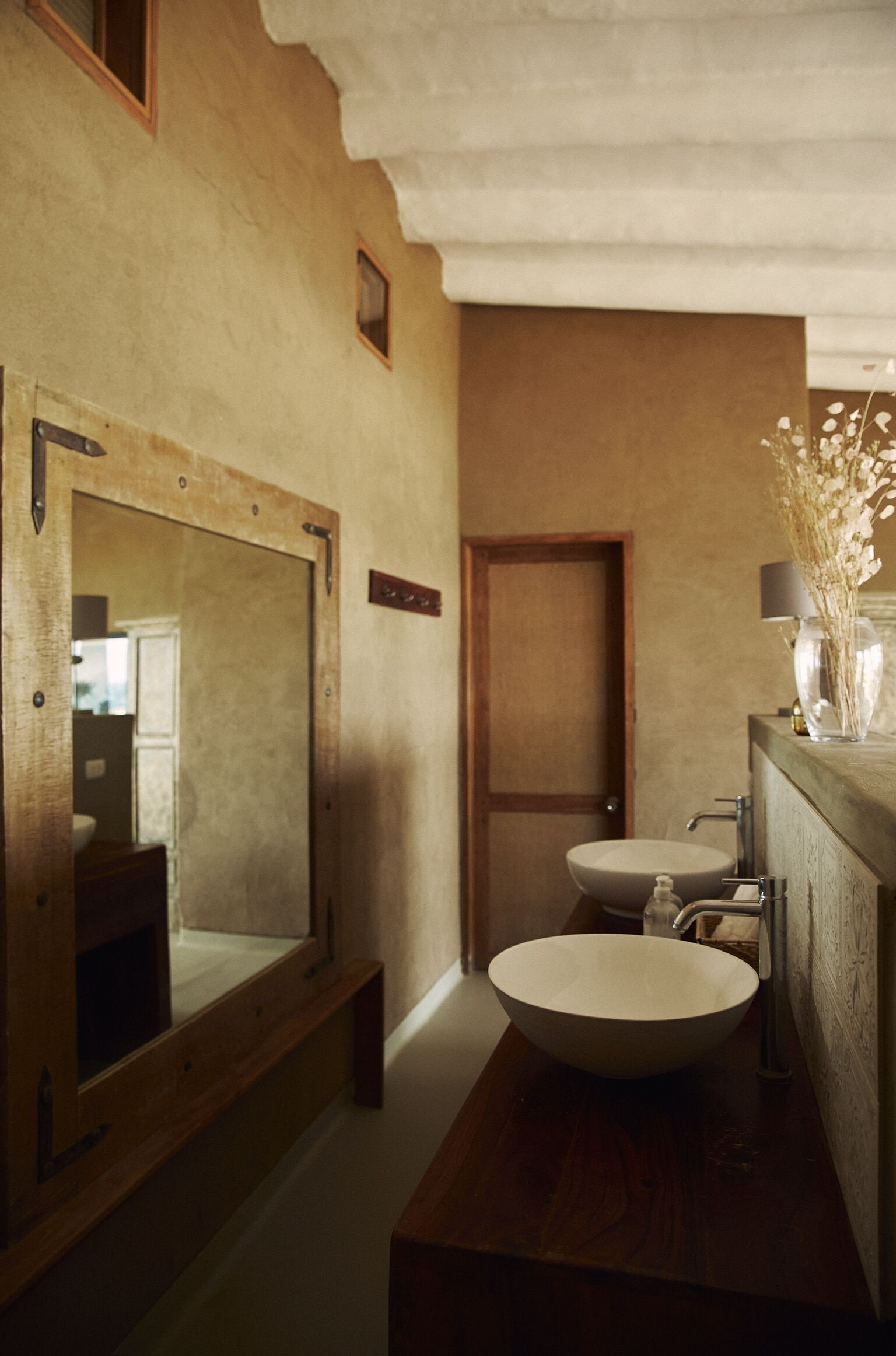 Une salle de bain avec un meuble-lavabo en bois, un lavabo rond et un grand miroir.
