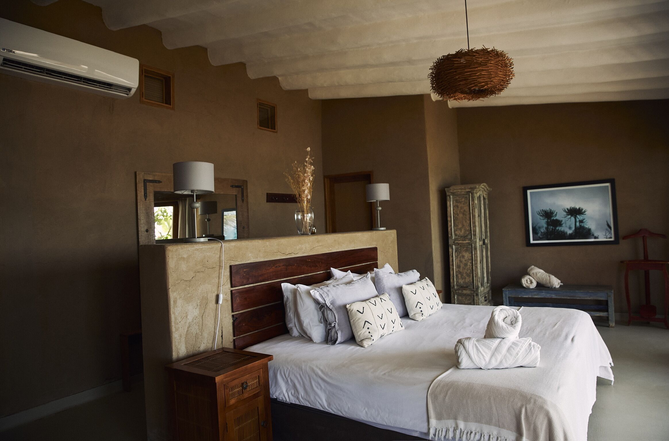 Een slaapkamer met een groot bed, nachtkastjes, een garderobe en een hanglamp.