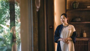 A person standing in a doorway with a wooden shelf in the background. - Avana Retreat (Bao La)