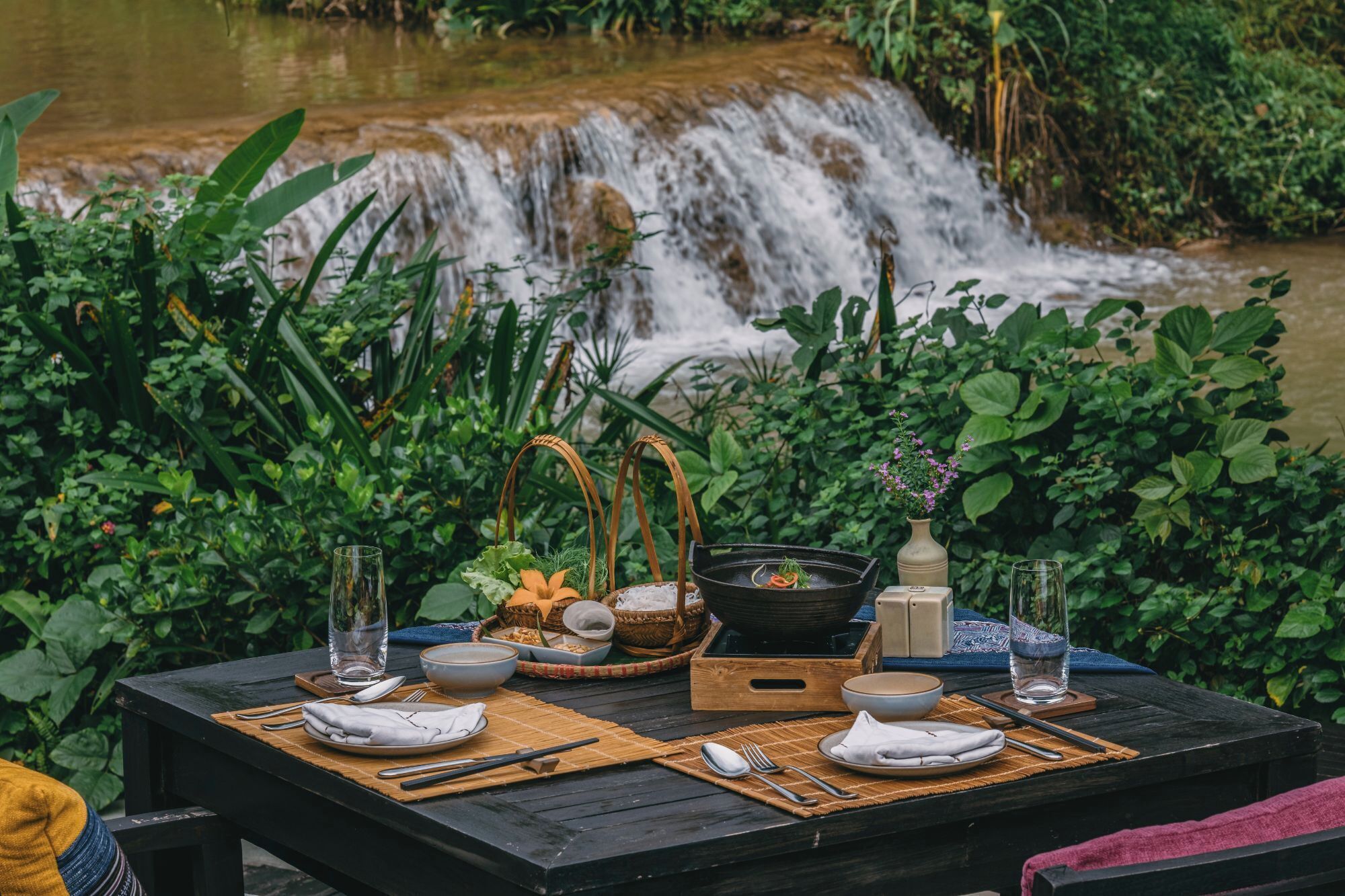 A table set outdoors with a waterfall in the background.