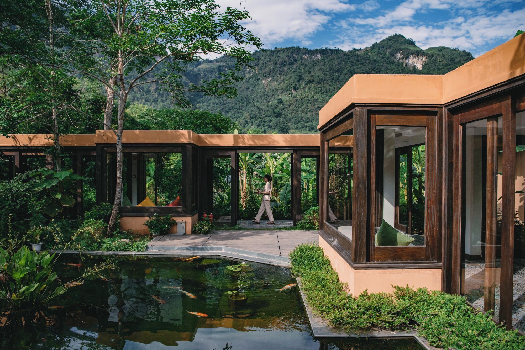 A modern building with large glass windows and a pond with koi fish.