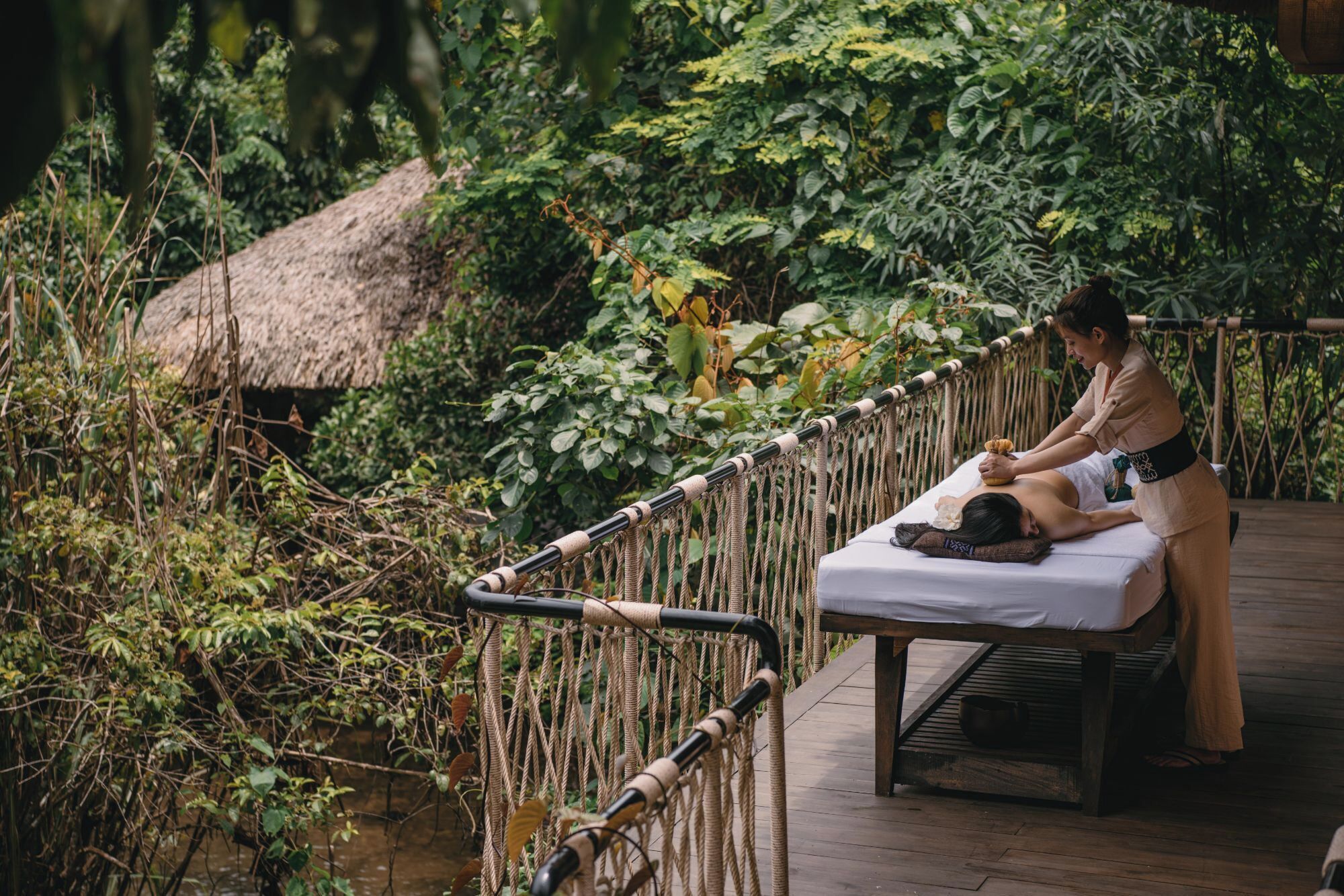 A massage therapy session on a wooden deck surrounded by lush greenery.