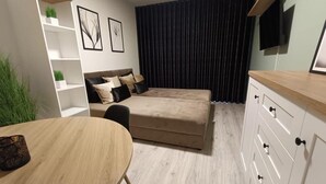 Une chambre à coucher moderne avec un lit, une commode en bois, une petite table et un téléviseur fixé au mur.