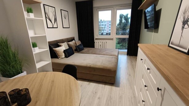 Un espace de vie compact comprenant un canapé, une table à manger et un téléviseur fixé au mur.