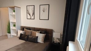 Une chambre moderne avec un grand lit, une table de chevet, une lampe et une fenêtre.