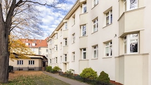 Ein mehrgeschossiges Wohnhaus mit gepflastertem Weg und niedrigem Zaun.