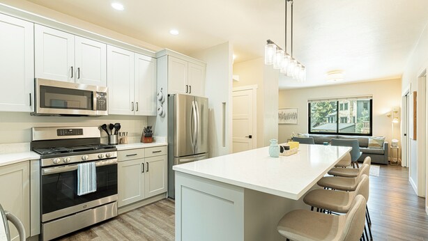 A modern kitchen with stainless steel appliances, white cabinetry, and a large island with bar stools. - Walk to Main Street & Town Lift, Private Hot Tub, Garage Parking, On Shuttle Route (Park City)