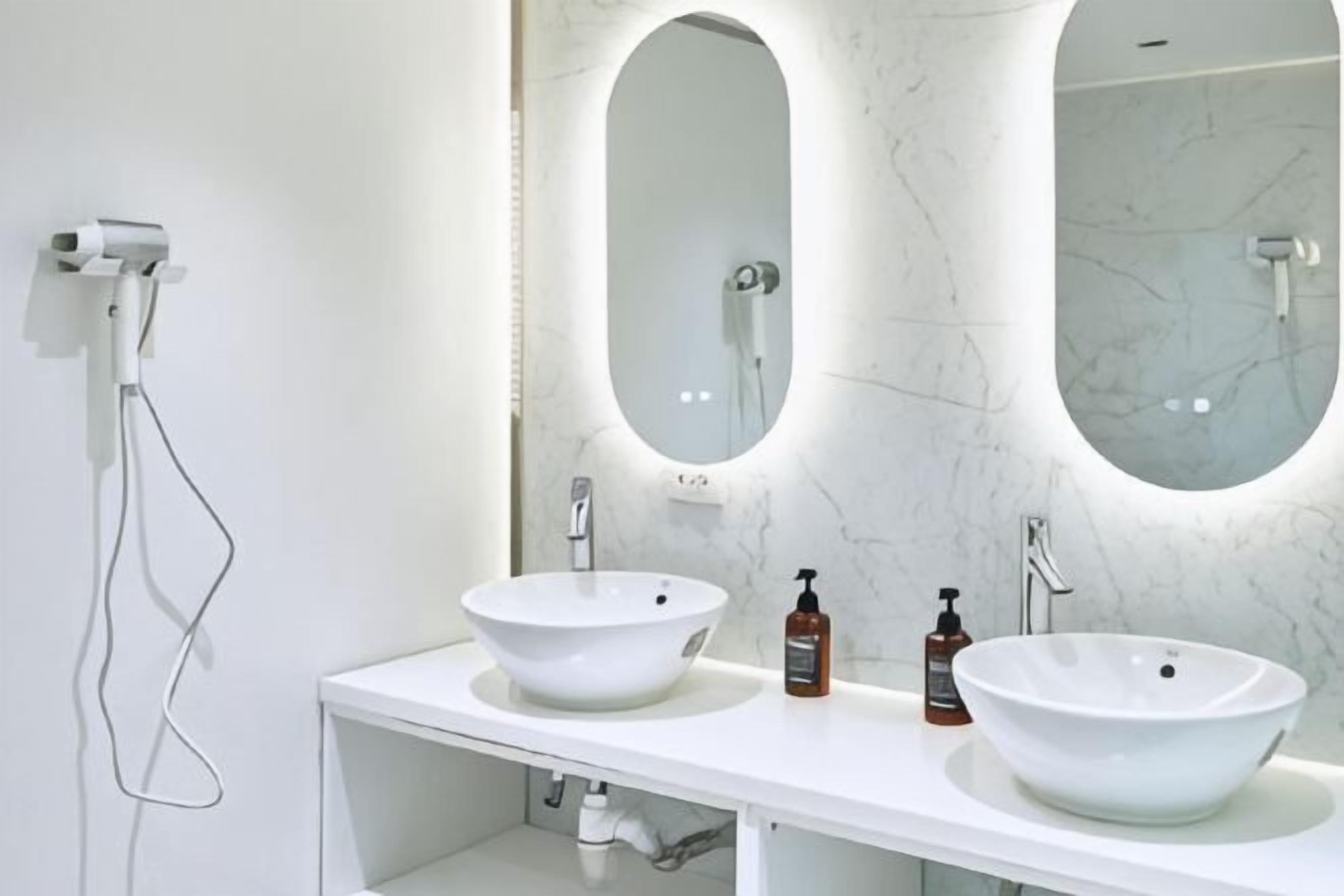 A bathroom with two white sinks, a large mirror, and a handheld showerhead.