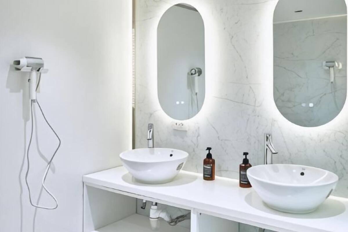 A bathroom with two white sinks, a large mirror, and a handheld showerhead.
