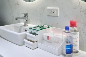 A bathroom sink with a mirror, a white drawer, and a bottle of hand soap. - Twin Star Inn (Taipei)