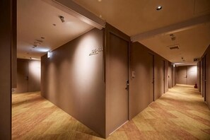 A hotel corridor with wooden flooring, beige walls, and doors with signage. - Twin Star Inn (Taipei)