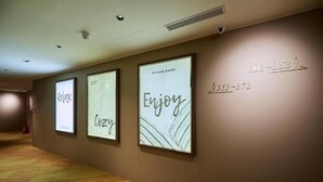 A hallway with framed artwork on the walls, a carpeted floor, and a sign with room numbers. - Twin Star Inn (Taipei)