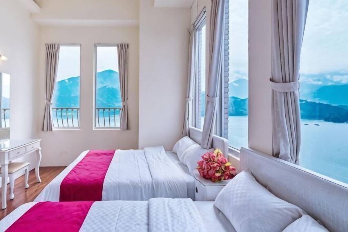 Ein Hotelzimmer mit zwei Betten, einem Schreibtisch und Meerblick.