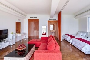 Ein modernes Hotelzimmer mit einem roten Sofa, einem Fernseher, einem Schreibtisch und einem Bett mit weißer Bettwäsche.