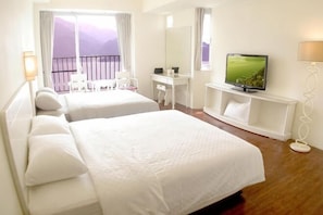 Ein Hotelzimmer mit zwei Betten, einem Schreibtisch, einem Fernseher und einem Balkon mit Blick.