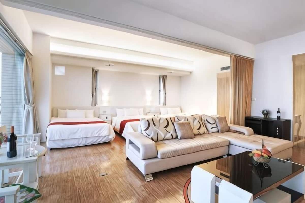 Ein Hotelzimmer mit Schlafsofa, Esstisch und getrennten Betten.