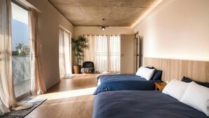 A bedroom with two beds, a large window, and a potted plant. - Living In Light　　　　　　 (Chiayi County)