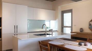 A modern kitchen with white cabinetry, a central island, and a dining area with a wooden table and chairs.