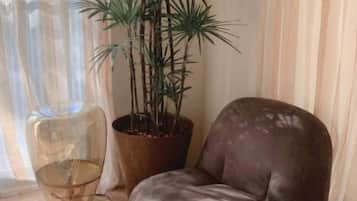 A room with a brown leather chair, a potted plant, and a clear glass chair.