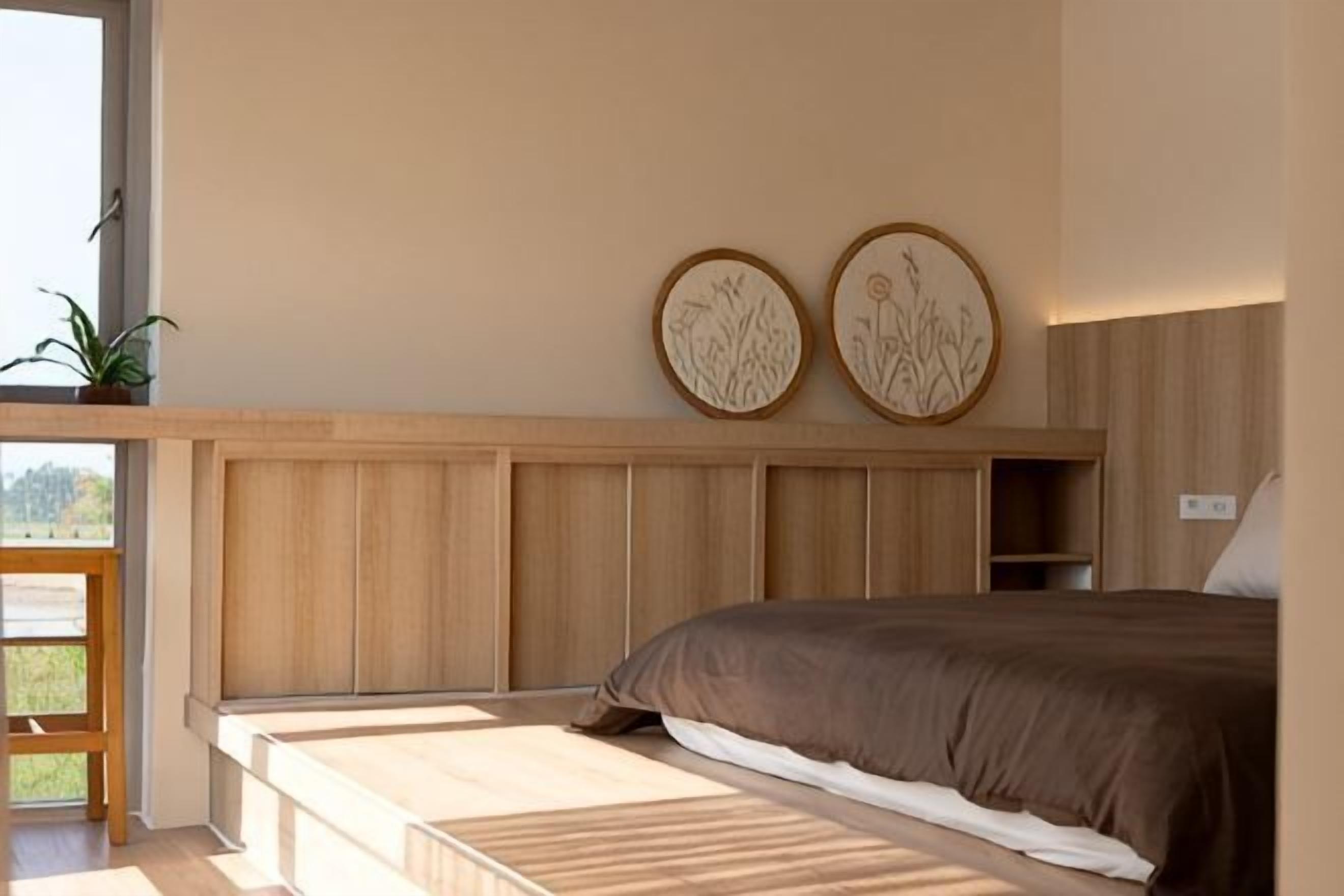 Un dormitorio con una cama, cabecera de madera y dos placas decorativas en la pared.