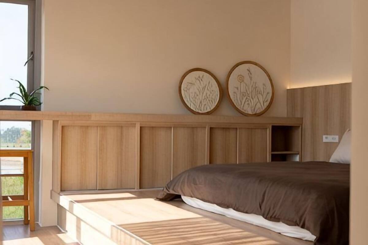 A bedroom with a bed, wooden headboard, and two wall-mounted decorative plates.