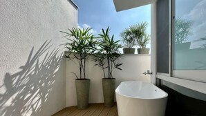 A small bathroom with a white bathtub, wooden flooring, and potted plants. - Living In Light　　　　　　 (Chiayi County)