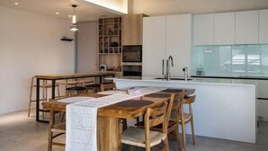A modern kitchen with white cabinets, a central island, and wooden chairs. - Living In Light　　　　　　 (Chiayi County)