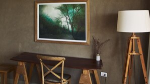 A room with a wooden desk, a chair, a lamp, and a framed painting on the wall. - Nimb Adobe by Wynwood House (Máncora)