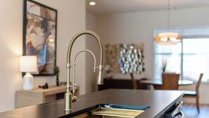 A modern kitchen with a stainless steel sink, a built-in oven, and a dining area with a chandelier. - Upscale 3BR Houston I Gated Parking I Relocation I Insurance Claim I Heights (Houston)