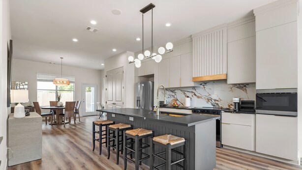 A modern kitchen with a central island, bar stools, and a dining area with a table and chairs. - Upscale 3BR Houston I Gated Parking I Relocation I Insurance Claim I Heights (Houston)