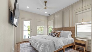 A bedroom with a bed, bedside table, and a TV mounted on the wall. - Upscale 3BR Houston I Gated Parking I Relocation I Insurance Claim I Heights (Houston)